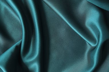 Mavi ipek kumaş ve avludan gelen döşeme kumaşı. Mavi saten, ipek kumaş, dalga, kumaş. Güzel tekstil arkaplanı. Yakın plan. Üst görünüm