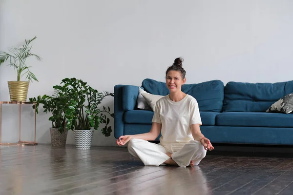 Spokojna brunetka uprawiająca jogę na łóżku w domu na podłodze — Zdjęcie stockowe
