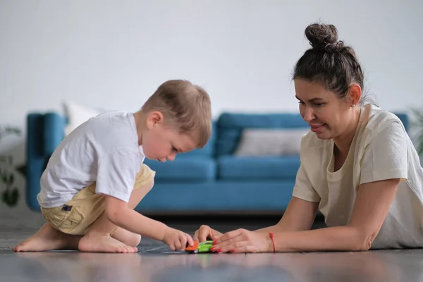 Uttrycksfull pojke leker med en leksaksbil med mamma. — Stockfoto