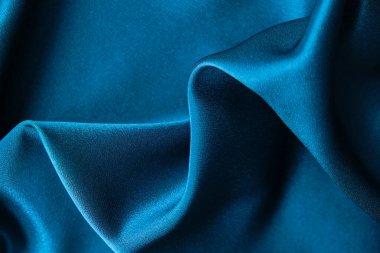Mavi ipek kumaş ve avludan gelen döşeme kumaşı. Mavi saten, ipek kumaş, dalga, kumaş. Güzel tekstil arkaplanı. Yakın plan. Üst görünüm
