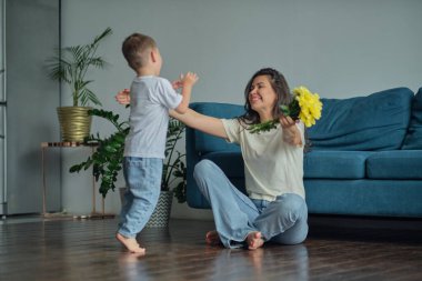 Anneler Günün kutlu olsun. Çocuk evlat tatilde annesini tebrik eder ve çiçek verir. Evde bayram kutlamaları sırasında anneler günü için onu tebrik etmek.