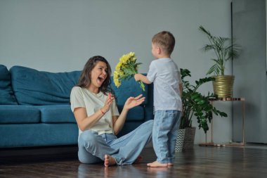 Anneler Günün kutlu olsun. Çocuk evlat tatilde annesini tebrik eder ve çiçek verir. Evde bayram kutlamaları sırasında anneler günü için onu tebrik etmek.
