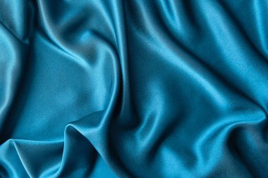 Mavi ipek kumaş ve avludan gelen döşeme kumaşı. Mavi saten, ipek kumaş, dalga, kumaş. Güzel tekstil arkaplanı. Yakın plan. Üst görünüm