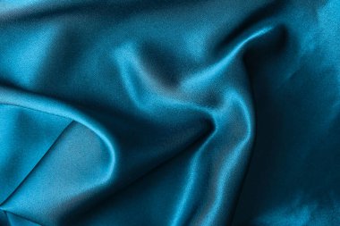 Mavi ipek kumaş ve avludan gelen döşeme kumaşı. Mavi saten, ipek kumaş, dalga, kumaş. Güzel tekstil arkaplanı. Yakın plan. Üst görünüm