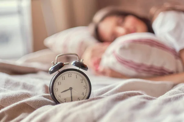 Mulher de meia-idade dormindo e despertador no quarto em casa. conceito de tempo de sono — Fotografia de Stock