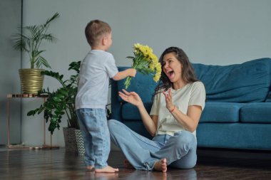 Anneler Günün kutlu olsun. Çocuk evlat tatilde annesini tebrik eder ve çiçek verir. Evde bayram kutlamaları sırasında anneler günü için onu tebrik etmek.