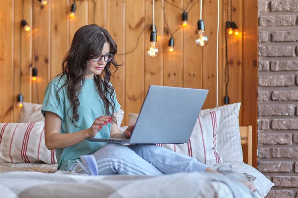 Gyönyörű középkorú nő ül az ágyon, és dolgozik egy laptop. a felnőttek átképzésének koncepciója, új szakma 30 év után — Stock Fotó