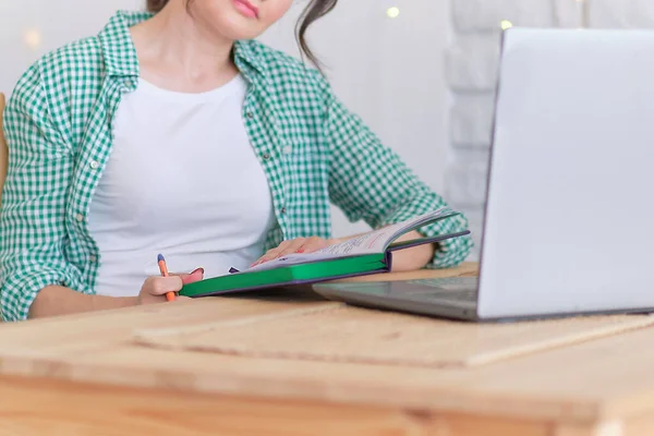 Egy nő ül egy asztalnál egy laptopnál. az otthonról történő távmunka fogalma. otthoni iroda a konyhában. hivatásos szabadúszó — Stock Fotó