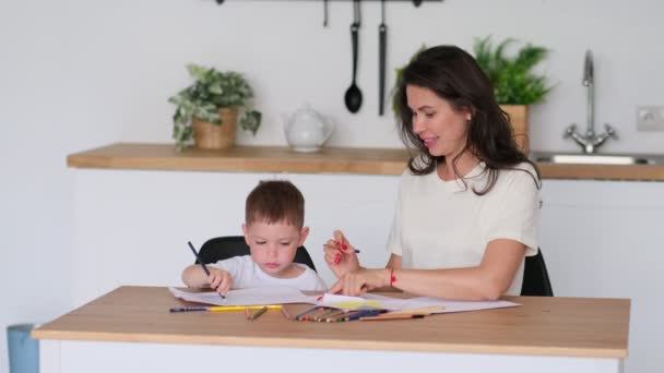 Мальчик учится рисовать. Мама и сын весело рисуют карандашами. Детское творчество. — стоковое видео