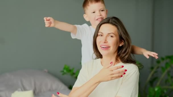 Moeder knuffelt met haar peuter zoontje samen op bed. Familiemomenten, kinderen geven erom. Moederschap, zwangerschapsverlof — Stockvideo