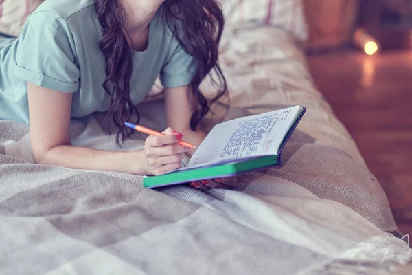 Lifestyle zacht beeld van mooie jonge vrouw zitten op haar gezellige bed en het maken van notities aan haar dagboek. Herfst seizoen stemming. — Stockfoto