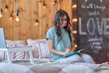 Düşünceli orta yaşlı kadın yatağında oturur ve düşüncelerini bir günlüğe yazar. Kadınlar konseptinde orta yaş krizi