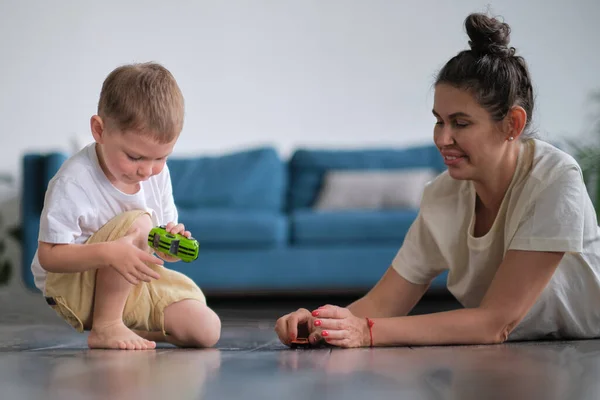 Expressive baby boy playing with a toy car with mother.