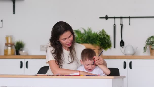 Mały chłopiec uczy się rysować. Mama i syn dobrze się bawią rysując ołówkami. Kreatywność dzieci. — Wideo stockowe