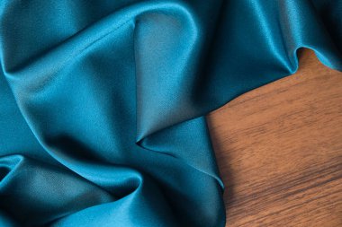 Mavi ipek kumaş ve avludan gelen döşeme kumaşı. Mavi saten, ipek kumaş, dalga, kumaş. Güzel tekstil arkaplanı. Yakın plan. Üst görünüm