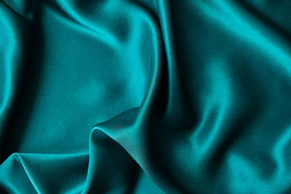 Mavi ipek kumaş ve avludan gelen döşeme kumaşı. Mavi saten, ipek kumaş, dalga, kumaş. Güzel tekstil arkaplanı. Yakın plan. Üst görünüm