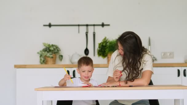 Mały chłopiec uczy się rysować. Mama i syn dobrze się bawią rysując ołówkami. Kreatywność dzieci. — Wideo stockowe