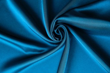 Mavi ipek kumaş ve avludan gelen döşeme kumaşı. Mavi saten, ipek kumaş, dalga, kumaş. Güzel tekstil arkaplanı. Yakın plan. Üst görünüm