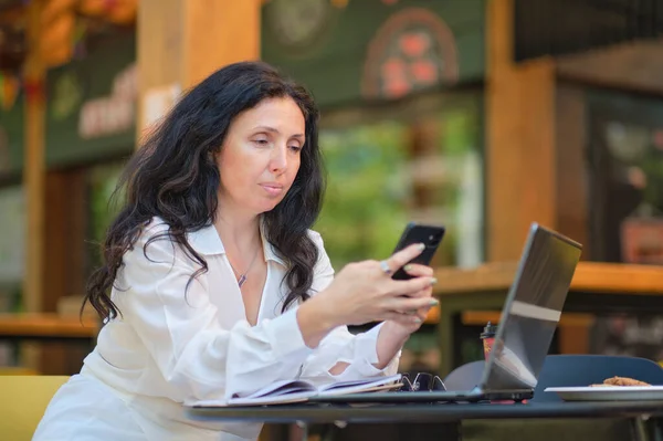 Usměvavá zralá podnikatelka pije kávu při práci v kavárně — Stock fotografie