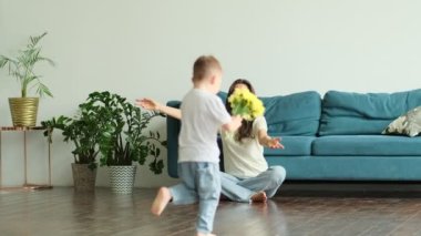 Anneler Günün kutlu olsun. Çocuk evlat tatilde annesini tebrik eder ve çiçek verir. Evde bayram kutlamaları sırasında anneler günü için onu tebrik etmek.