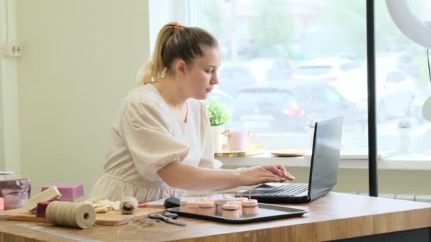 Small business owner. Portrait of mature woman standing at her shop behind the laptop and smiling. female online store seller entrepreneur packing package post shipping box preparing delivery parcel. — Stock Video
