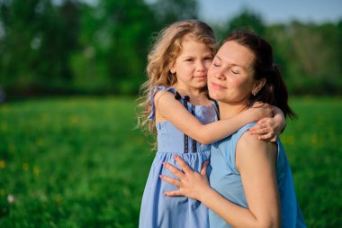 Açık havada aile hayatı olan bir doğa sahnesi. Anne ve küçük kızı parkta birlikte oynuyorlar. Mutlu aile kavramı. Aile hayatında mutluluk ve uyum..