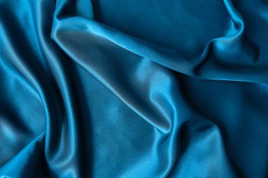 Mavi ipek kumaş ve avludan gelen döşeme kumaşı. Mavi saten, ipek kumaş, dalga, kumaş. Güzel tekstil arkaplanı. Yakın plan. Üst görünüm