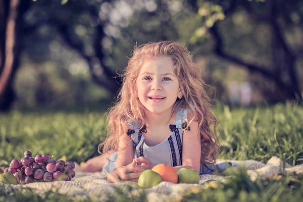 Feliz niña divirtiéndose en el parque. Lindo niño sentado en la hierba en un día soleado de verano. — Foto de Stock