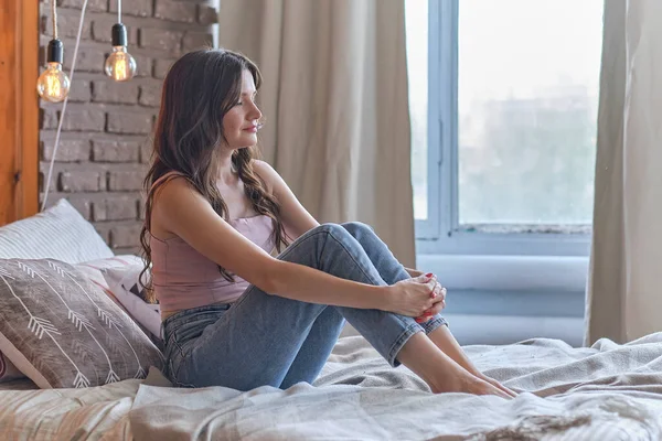 Overstuur brunette vrouw zittend op het linnen in bed thuis. depressieve vrouw na echtscheiding. — Stockfoto