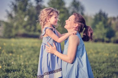 Açık havada aile hayatı olan bir doğa sahnesi. Anne ve küçük kızı parkta birlikte oynuyorlar. Mutlu aile kavramı. Aile hayatında mutluluk ve uyum..