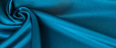 Mavi ipek kumaş ve avludan gelen döşeme kumaşı. Mavi saten, ipek kumaş, dalga, kumaş. Güzel tekstil arkaplanı. Yakın plan. Üst görünüm