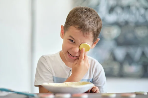 Taller para niños. Los niños aprenden a usar la arcilla para hacer platos hermosos. Taller, clase magistral. chico divertido con una muestra cierra el ojo con una muestra de trabajo de cerámica. — Foto de Stock