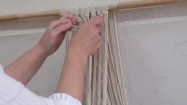 Makrome 'un temel düğümleri, kadın elinin omuz arkasının görüntüsü, düğümleniyor. Çevre dostu modern örgü doğal dekorasyon konsepti.