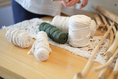 Masada beyaz iplik ve kırsal çubuklar var. Makrome ve el sanatları afişleri için iyidir. Doğal dekorasyon kavramı.