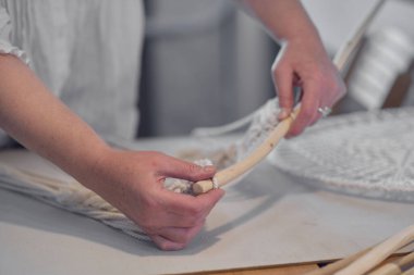 Yaratıcı bir masaüstü üzerinde aletlerle özel makrome dekor üzerinde çalışan bir kadın yukarıdan izleniyor. Hobi örgü örme el ve iplik makromu.