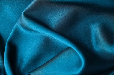 Mavi ipek kumaş ve avludan gelen döşeme kumaşı. Mavi saten, ipek kumaş, dalga, kumaş. Güzel tekstil arkaplanı. Yakın plan. Üst görünüm