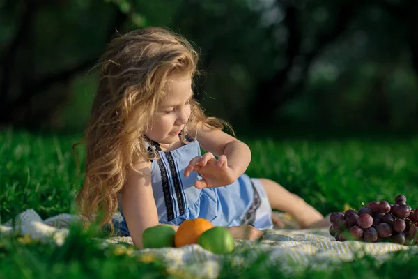 Menina feliz se divertindo no parque. Criança bonito sentado na grama em um dia ensolarado de verão. — Fotografia de Stock