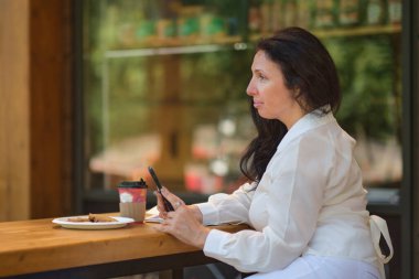 Neşeli, zarif, yaşlı bir kadın akıllı bir telefonla arkadaşlarıyla gülümsüyor..