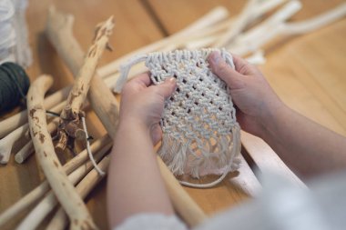 Makrome 'un temel düğümleri, kadın elinin omuz arkasının görüntüsü, düğümleniyor. Çevre dostu modern örgü doğal dekorasyon konsepti.