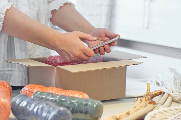 Femme entrepreneur emballe une commande dans une boîte en carton à envoyer par une entreprise de messagerie. une femme âgée crée une entreprise à partir de son passe-temps. — Photo