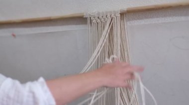 Makrome 'un temel düğümleri, kadın elinin omuz arkasının görüntüsü, düğümleniyor. Çevre dostu modern örgü doğal dekorasyon konsepti.