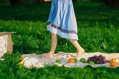 Çıplak ayaklı kız parkta çimlerin üzerinde yürüyor. Bir kızın bıçakları...