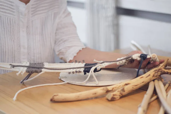 Femme travaillant sur un décor macrame personnalisé avec des outils sur un bureau créatif regardé d'en haut. Hobby tricot macramé de la main et du fil. — Photo