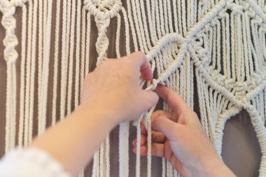 El yapımı makrome doku deseni yakın plan. ECO dostu modern örgü doğal dekorasyon konsepti. Güzel boho makrome duvar paneli rahat bir atmosfer ekler.