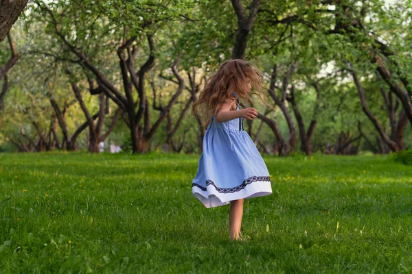 Meisje rent blootsvoets op het gras. gelukkig kind op een hete zomerdag. — Stockfoto