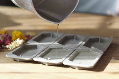 Kadın mum yapmak için silikon kalıba balmumu döker.