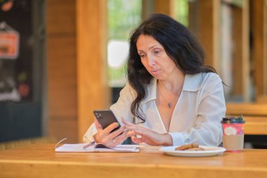 Neşeli, zarif, yaşlı bir kadın akıllı telefondan arkadaşlarıyla sohbet ediyor. Yaşlılar için randevu siteleri.