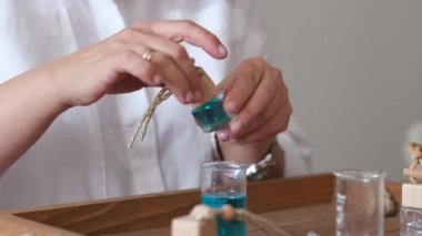 Yağlı ve cam şişeli bir pipetin yakın çekimi. Kadın şişeye parfüm döküyor. Parfüm atölyesi oluşturma.