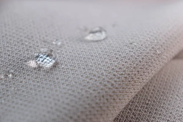 Abalorios de agua en la tela. Fondo de revestimiento impermeable con gotas de agua. enfoque suave, desenfoque —  Fotos de Stock