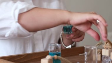Yağlı ve cam şişeli bir pipetin yakın çekimi. Kadın şişeye parfüm döküyor. Parfüm atölyesi oluşturma